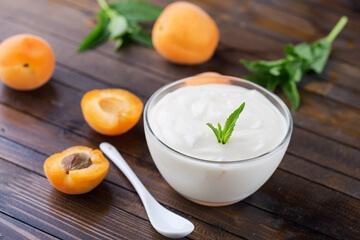 frischer Joghurt, daneben liegen Aprikosenhälften. Für unser leckeres Joghurteis.